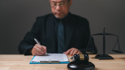 lawyer professional in a suit is writing on a piece of paper. Concept of formality and professionalism, as the man is dressed in a suit and tie and is writing on a desk. The presence of a gavel