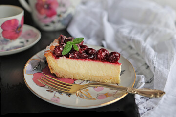 Appetizing portioned piece of cottage cheese tart and cherries on a porcelain plate.