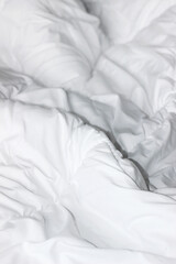 Fototapeta na wymiar Unmade Bed with Fluffy White Duvet Blanket. Hotel Comfort Sleep Concept. 