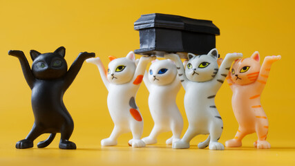 Toy dancing kittens carrying a black coffin. Concept of a funeral procession dancing with a coffin....