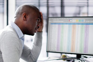 Unhappy African man using spreadsheets