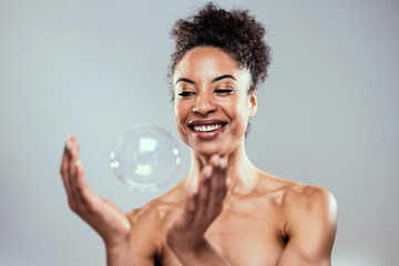 Attractive mature woman playing with soap and water bubbles on isolated white