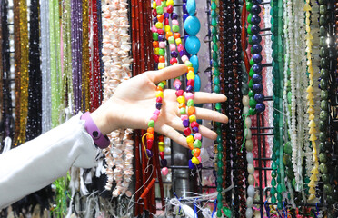 hand of a girl while she is choosing a colorful pearl necklace in the handcrafted accessories stall