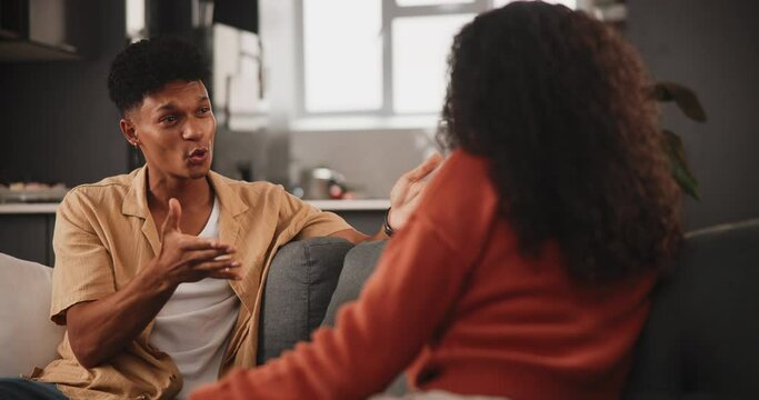 Angry, couple and fight with conflict in dispute, disagreement or argument on sofa at home. Frustrated man or woman shouting for breakup in toxic relationship, divorce or cheating affair at the house