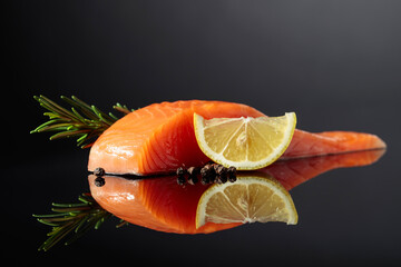 Smocked salmon with rosemary, lemon, and peppercorn on a black background.