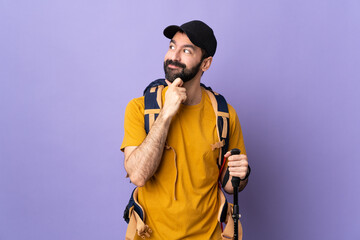 Caucasian handsome man with backpack and trekking poles over isolated background thinking an idea while looking up