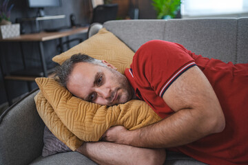 Man alone at home lying on sofa looking sad and distraught