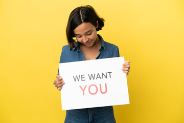 Young mixed race woman isolated on yellow background holding We Want You board