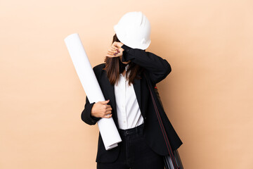 Young architect woman holding blueprints over isolated background covering eyes by hands - 783602510