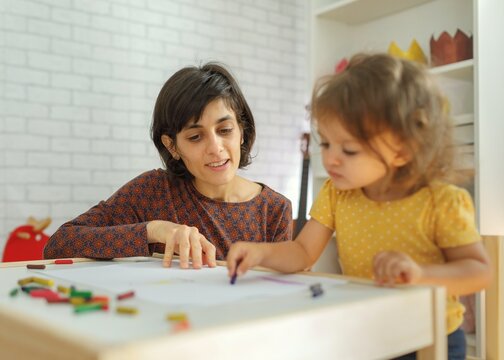 Mother and daughter sitting on the table and drawing. Learning with kids concept