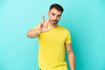 Fototapeta premium Young caucasian man isolated on blue background happy and counting three with fingers
