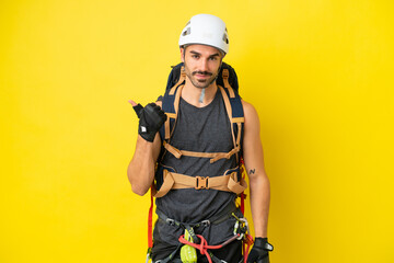 Young caucasian rock climber man isolated on yellow background pointing to the side to present a...