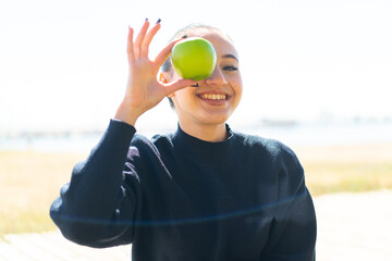 Young moroccan girl  at outdoors holding an apple with happy expression