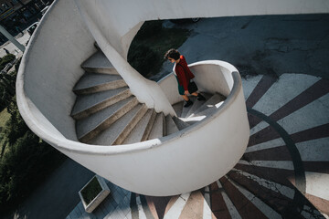 Elevated view of a businesswoman walking down a spiral staircase, symbolizing progress and career...