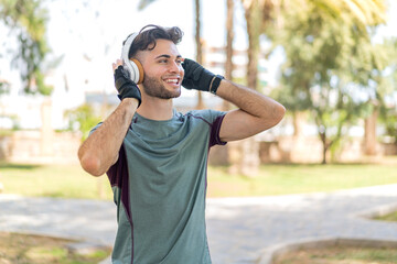 Young handsome man wearing sport wear and listening music with headphones