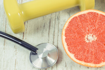 Ripe grapefruit and dumbbells for fitness. Fruits as source minerals and vitamins
