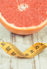 Ripe grapefruit and tape measure on rustic board. Fruits as source minerals and vitamins