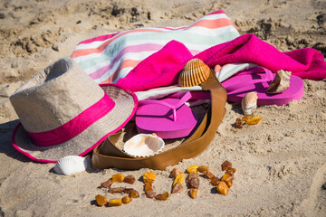 Inscription sun made of amber and different accessories for relax on sand. Straw hat, slippers and towel. Summer time on beach
