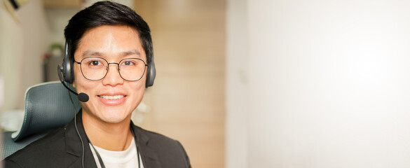 close up asian man call center agent wear headset device and smiling working in operation room with service-mind at desktop table for telemarketing and help desk background concept	