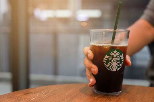 Bangkok,Thailand- March 27,2024 : close up man hand hold glass of Americano flavor coffee style at Starbuck cafe for city lifestyle concept