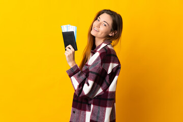 Young Ireland woman isolated on yellow background happy in vacation with passport and plane tickets