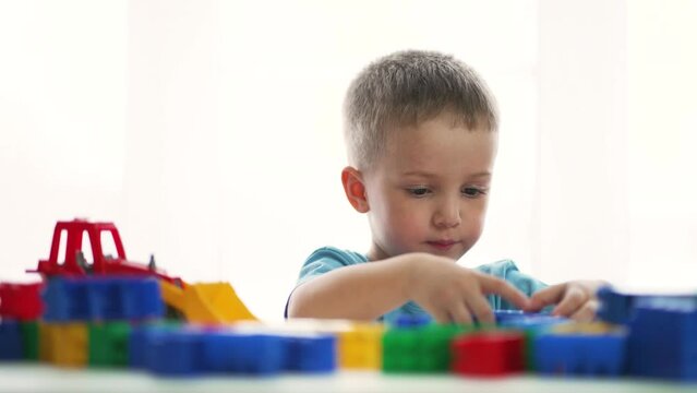 Teamwork of children in kindergarten. Brother and sister play blocks at table in colored toys. Preschool education in kindergarten. Children play with toys. Home games in the family. Home kindergarten