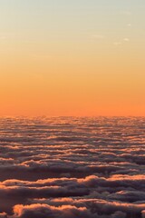 Vertical shot of the colorful and half-cloudy sunset with the view over the clouds