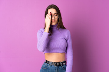 Young woman over isolated purple background with headache