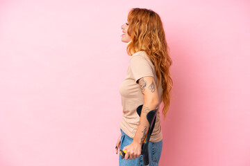 Young caucasian woman wearing neck brace isolated on pink background laughing in lateral position