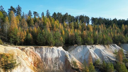 Aerial shot of beautiful autumn trees near a sand quarry on a sunny fall day