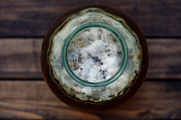 Dangerous mold in a glass jar with sweet drink, closeup, top view. Mold is very dangerous to health. Virus particles, fungus in the drink, old mold in the liquid - 783627750