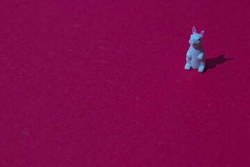 High-angle view of a white rabbit on right up corner of a red surface