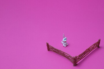 White rabbit with a small fence on the pink background