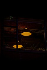 Vertical shot of a pair of yellow ceiling lights behind a window at night