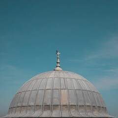 Fototapeta na wymiar Closeup of a bird perched on top of Suleymaniye Mosque against a blue sky in Istanbul, Turkey