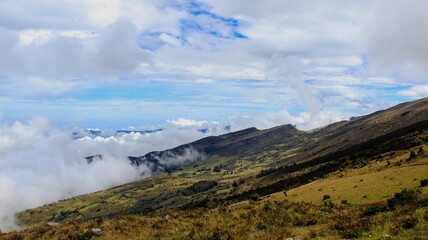 Beautiful white fluffy clouds in blue sky over green valley on mountainside