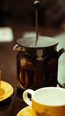 Vertical closeup of a brewing coffee on a table with empty cups
