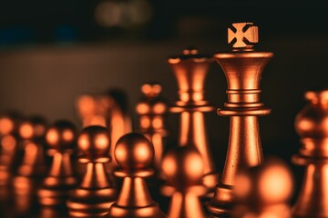 Closeup of gold metallic chess pieces on a board