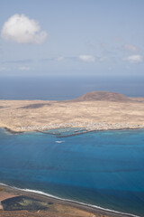 Views of the island of La Graciosa from the viewpoint of El Rio. Turquoise ocean. Blue sky with big white clouds. Caleta de Sebo. Town. volcanoes. Lanzarote, Canary Islands, Spain