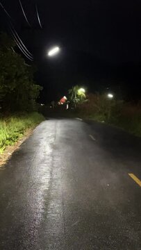 Evaporating moisture on a curvy road after a nocturnal downpour, with dimly lit surroundings