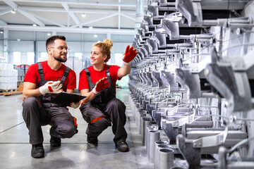 Factory engineers checking production machine and inspecting parts.