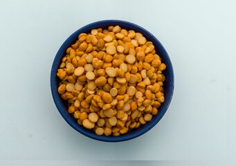 Bowl containing yellow split chickpeas on a white background