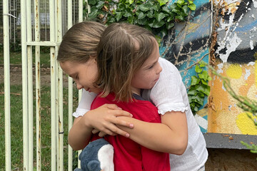 Little girls friends support each other, hug and help to survive emotions after the school