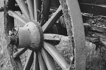 Grayscale close-up shot of an aged metallic carriage wheel