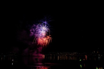 Beautiful bright firework explosions over Lake Zurich at night