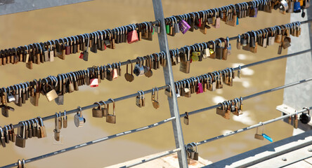 Close-up shot of love keylocks hanging on fence pipes.