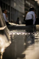 Meubelstickers Selective focus shot of the water in a fountain with a group of Jewish kids beside it in Milan © Wirestock