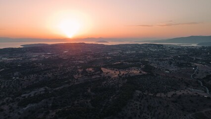 Bird's eye view of a green island against the sea at sunset