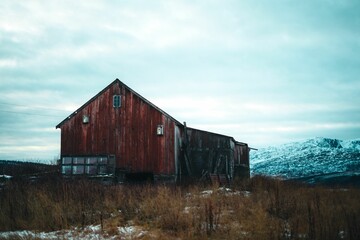 Old wooden building and rocky mountains covered with snow, Tromso, Norway