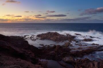 Beautiful view of ocean waves in a rocky beach during sunset